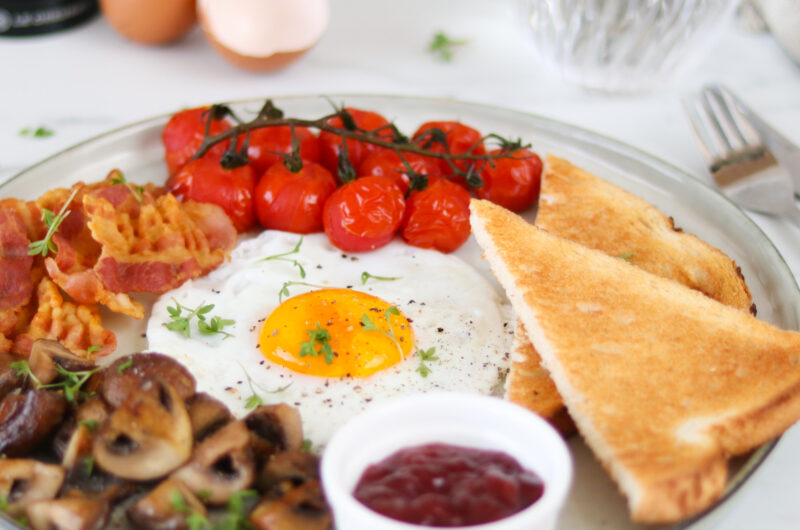 Uitgebreid ontbijt met ei, spek, champignons en tomaat